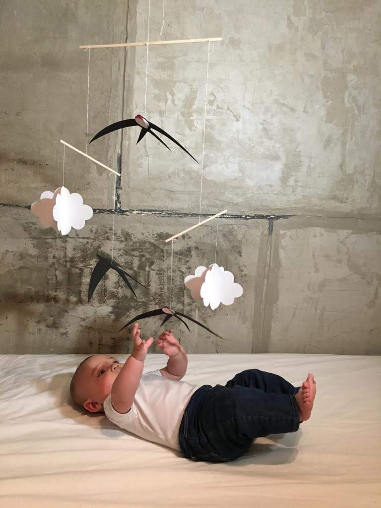 A baby reaching for the Montessori Swallows mobile.