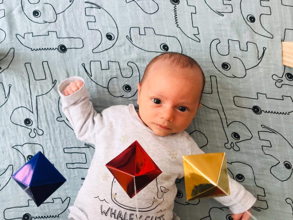 A baby boy is observing the Montessori Octahedron mobile