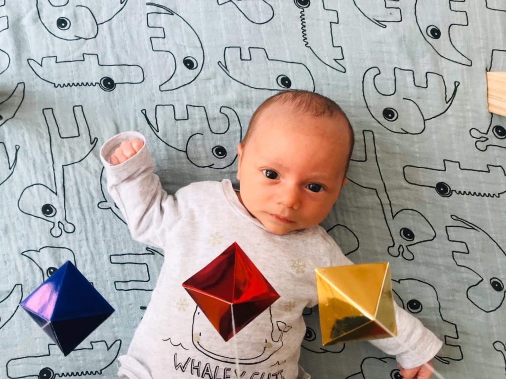 A baby is observing the Octahedron mobile,el Móvil Montessori Octaedro