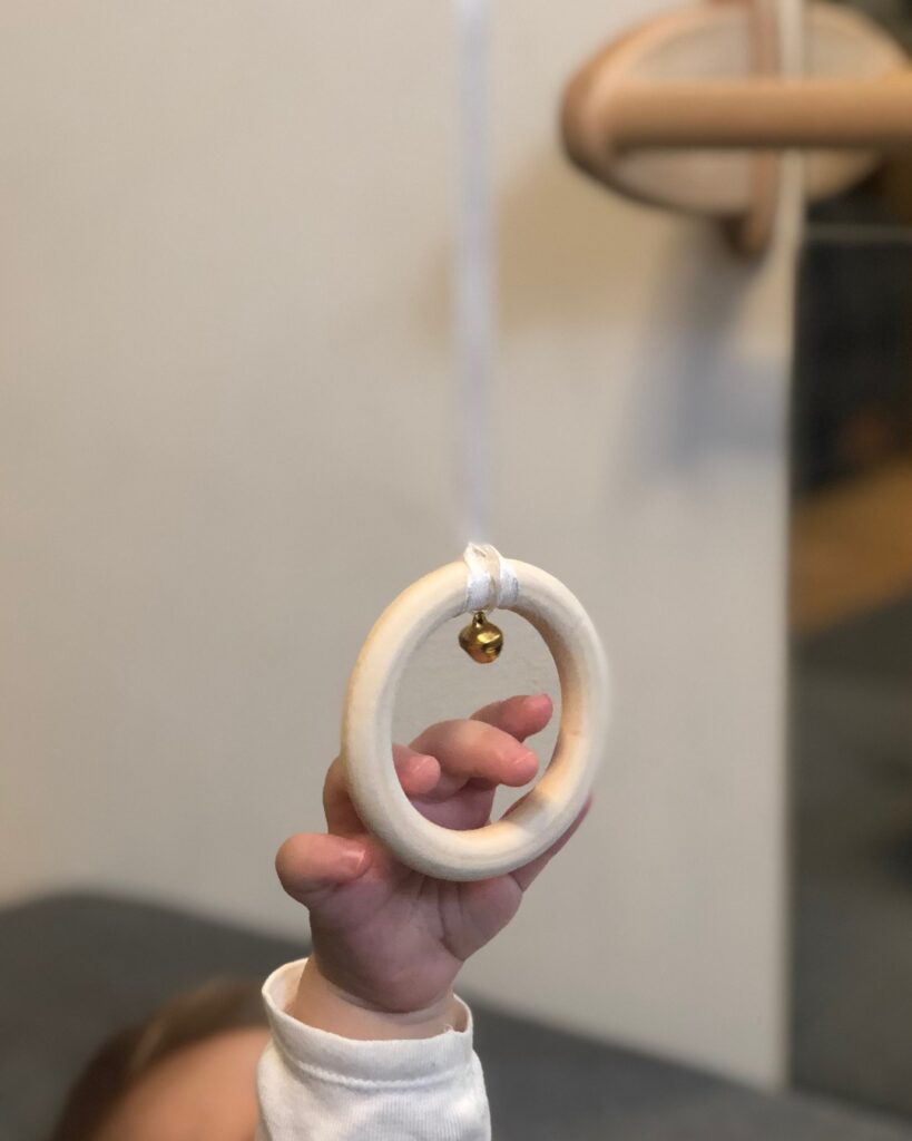 baby hand holding wooden ring montessori tactile mobile