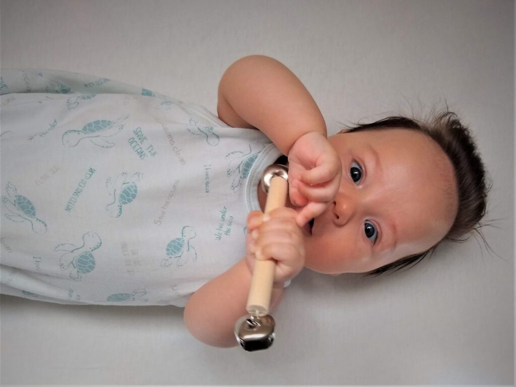 Montessori Bell Rattle in a baby boy's hand
