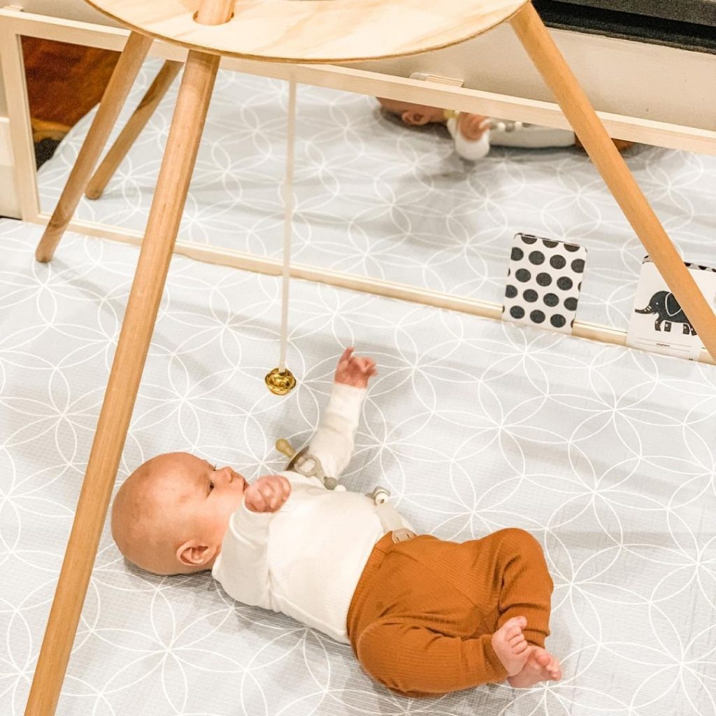 A baby is observing the Ring on a Ribbon mobile