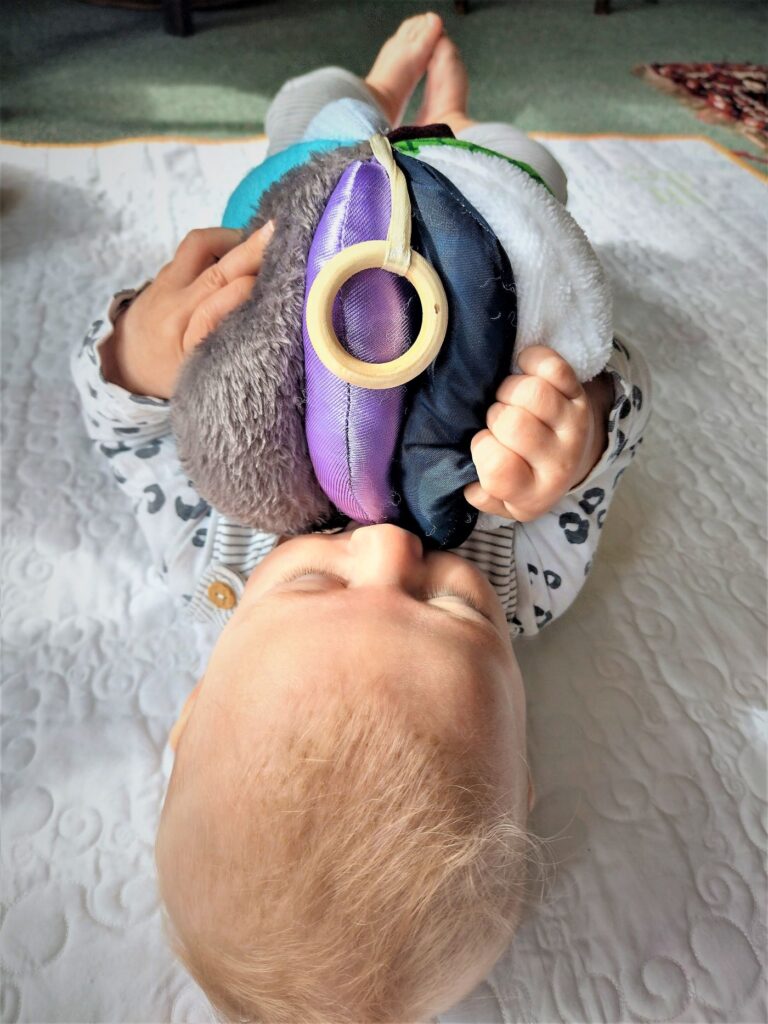 baby holding fabric sensory ball grasping textures