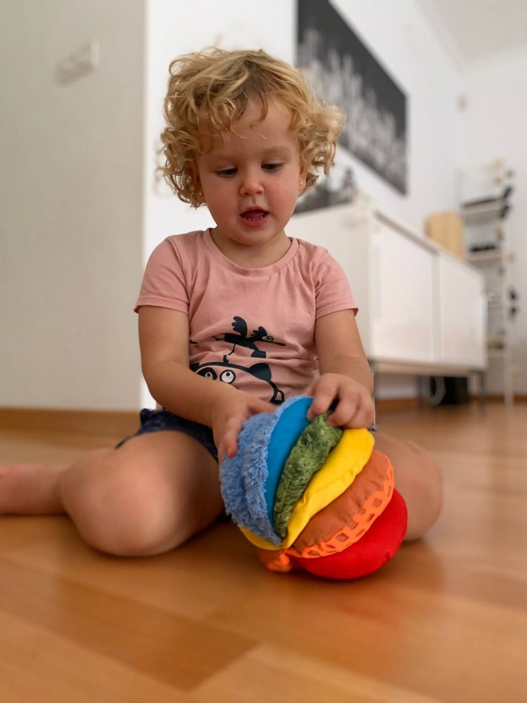 A toddler is exploring the Fabric Sensory Ball.
