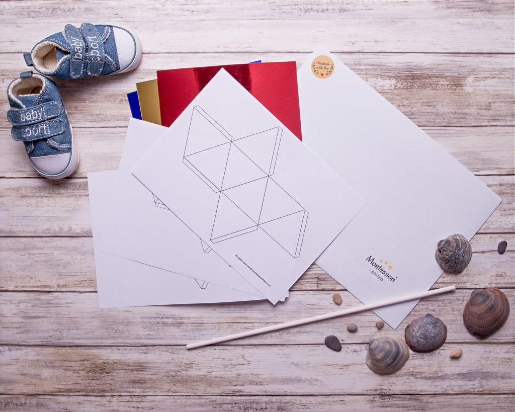 Flatlay of DIY Montessori Octahedron Mobile resources with pre-cut paper shapes, strings, and dowel arranged for easy assembly.