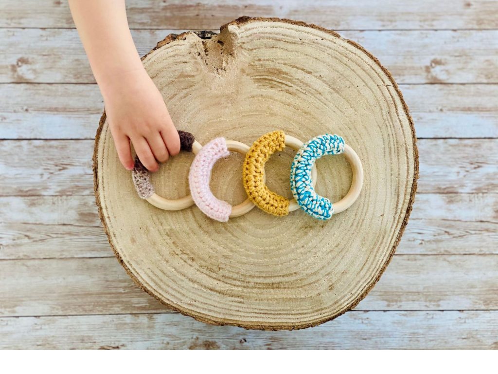 baby holding crochet teething ring for grasping and teething