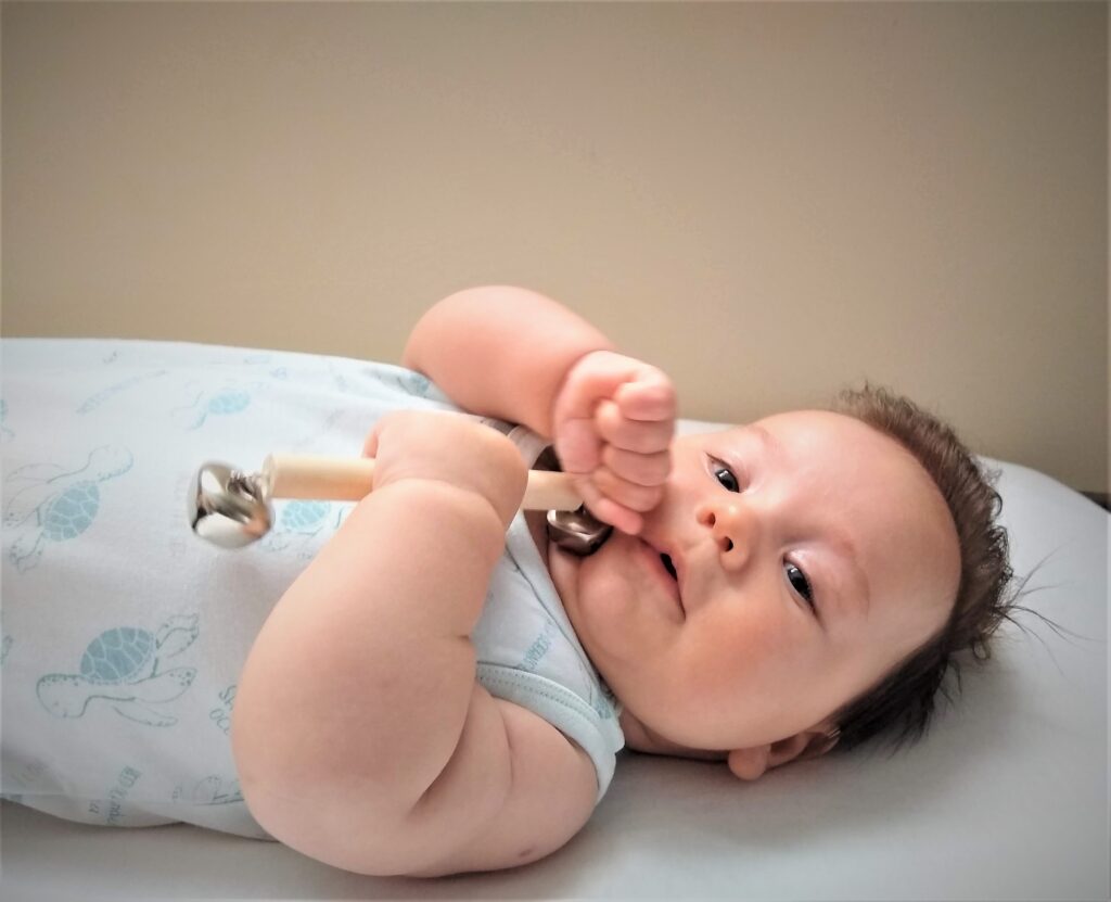 Montessori csengettyűs csörgő baba kezében