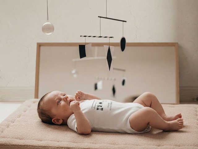 montessori baby lying on movement mat observing munari mobile with floor mirror - Montessori Alternatives